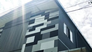 A modern building with a geometric facade, large windows, and visible power lines. - TF Apartment (Chiang Mai)