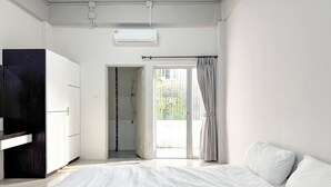 A bedroom with a bed, a wardrobe, a shower, and a view of the outdoors. - TF Apartment (Chiang Mai)