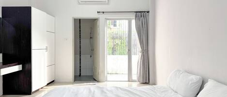Un dormitorio con cama, armario, ducha y vistas al exterior.