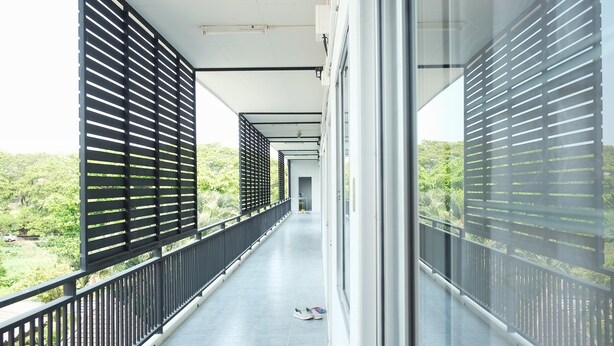 A long, narrow balcony with black metal railings and a tiled floor, overlooking a lush green landscape. - TF Apartment (Chiang Mai)