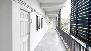 A corridor with a tiled floor, white doors, and a black railing. - TF Apartment (Chiang Mai)