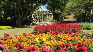 Un jardín con una escultura metálica esférica rodeada de flores coloridas.