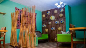 A room with a wooden floor, a green sofa, a wooden partition with decorative plates, and a chandelier. - Pilgrims Brook Hotels Ltd (Lagos)