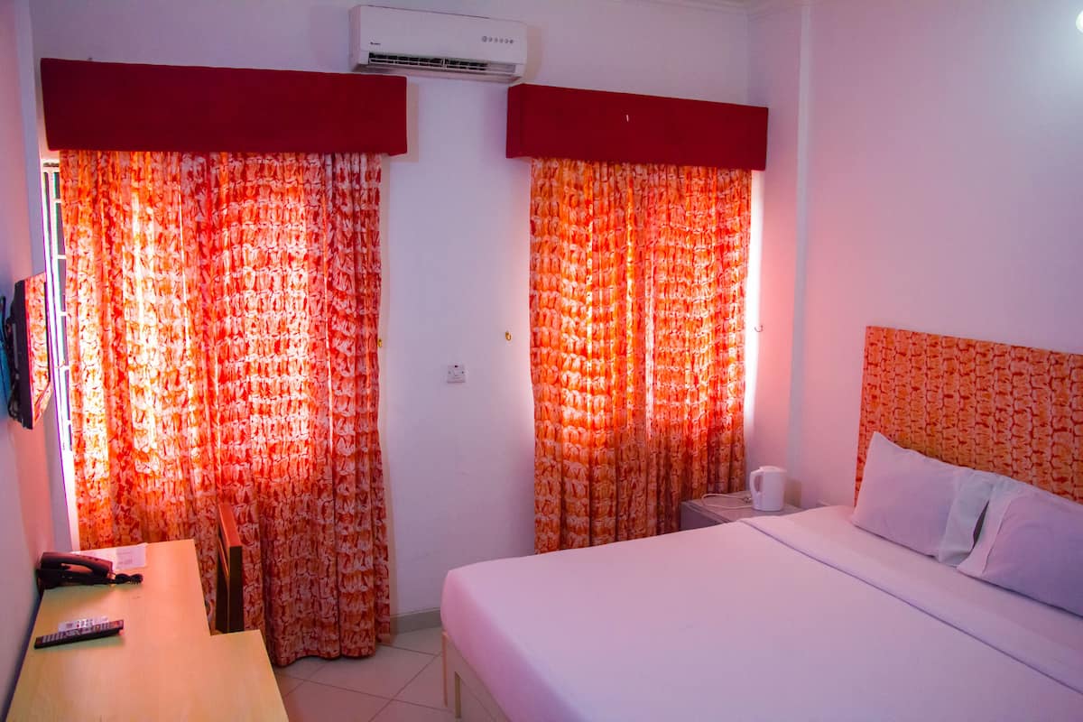 A hotel room with a bed, a desk, and curtains.