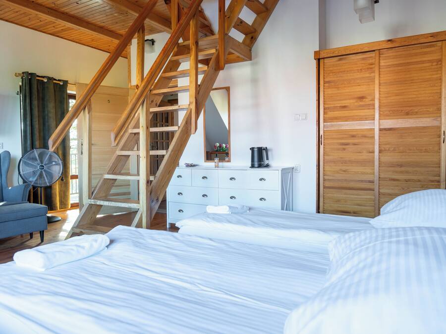 Un dormitorio con cama, cómoda, silla, ventilador y una escalera de madera.