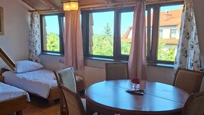 A cozy room with wooden floors, a round table, and two beds. - Villa Zosieńka (Gdansk)