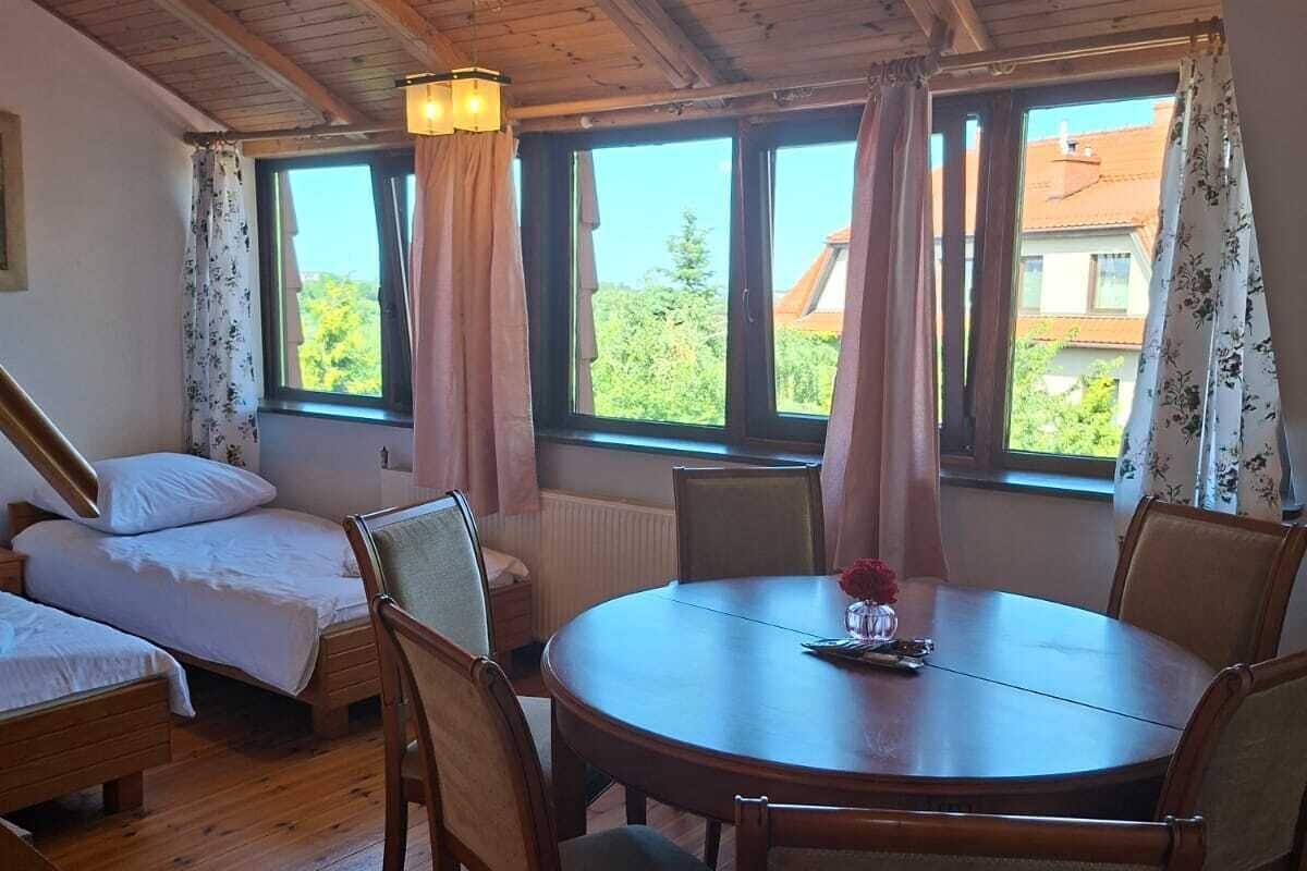 Una habitación acogedora con pisos de madera, una mesa redonda y dos camas.