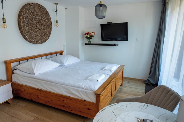 A neatly made bed with white linens, a wooden headboard, and a small bedside table.