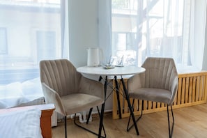 A room with a round table, two chairs, a white kettle, and a window with a view of the outside. - Villa Zosieńka (Gdansk)