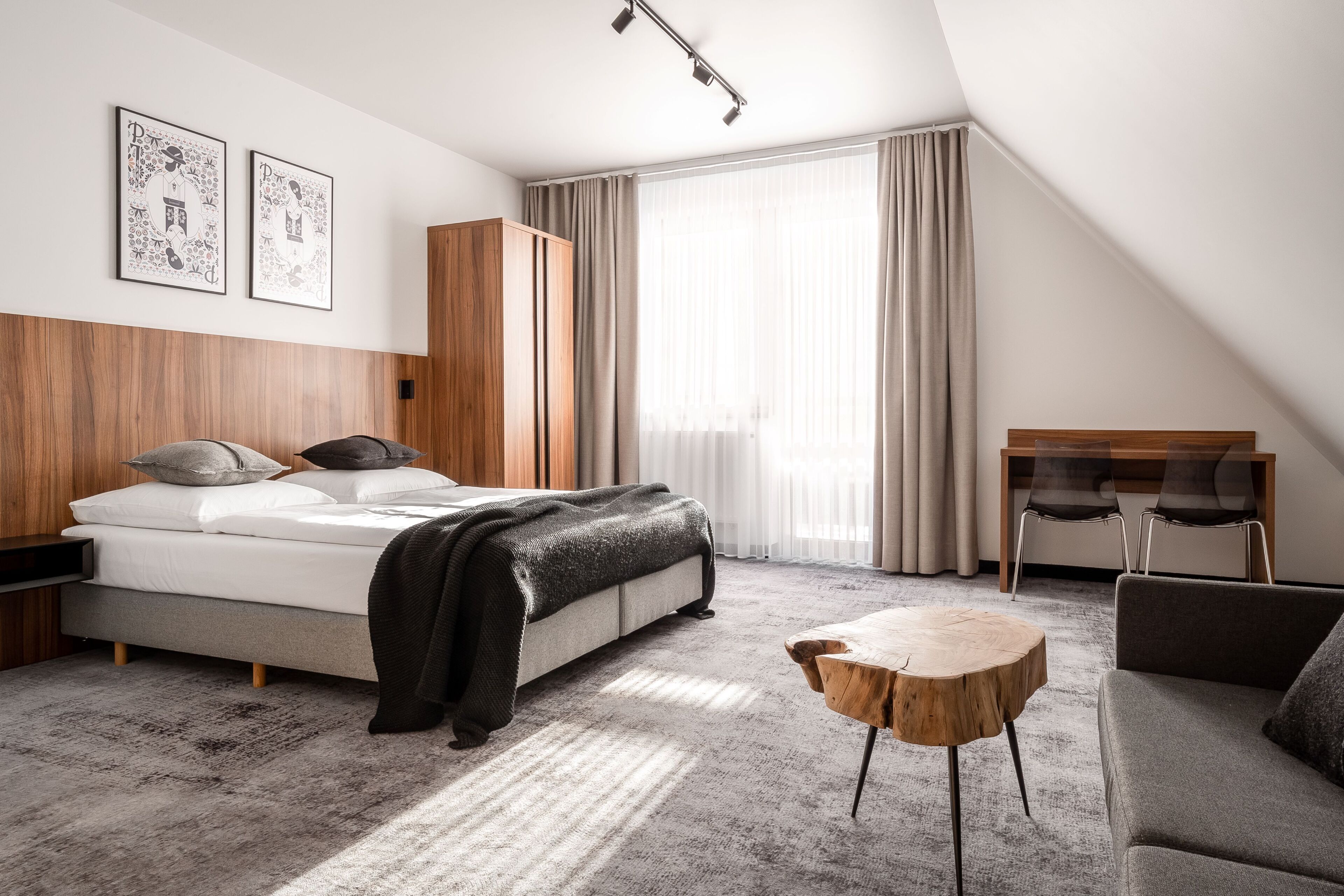 A modern hotel room with a bed, a small table, a sofa, and a desk.