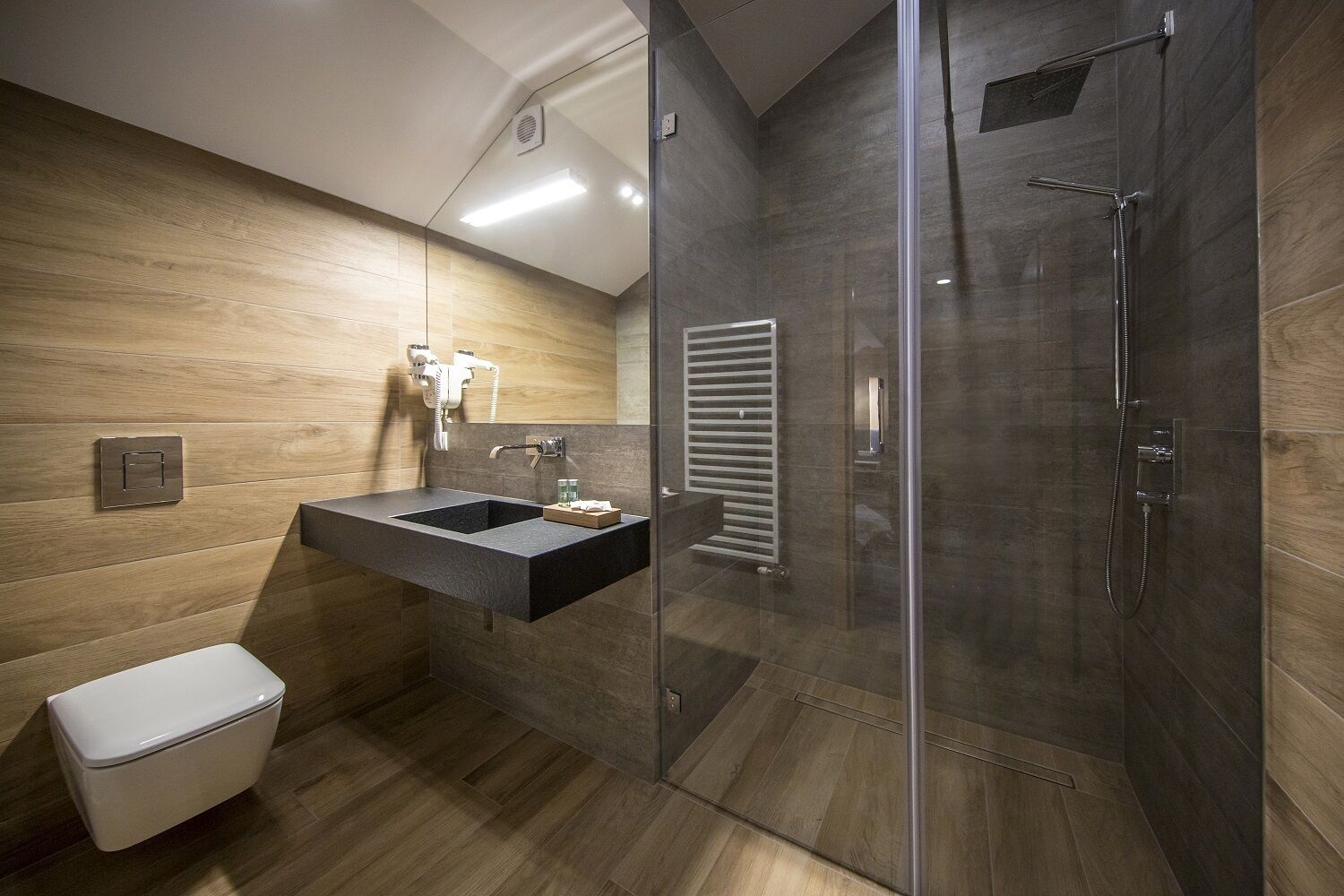 Un bagno moderno con doccia vetrata, lavabo integrato con specchio e WC.