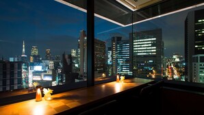 Una habitación de hotel moderna con un amplio ventanal que ofrece vistas a la ciudad de noche.