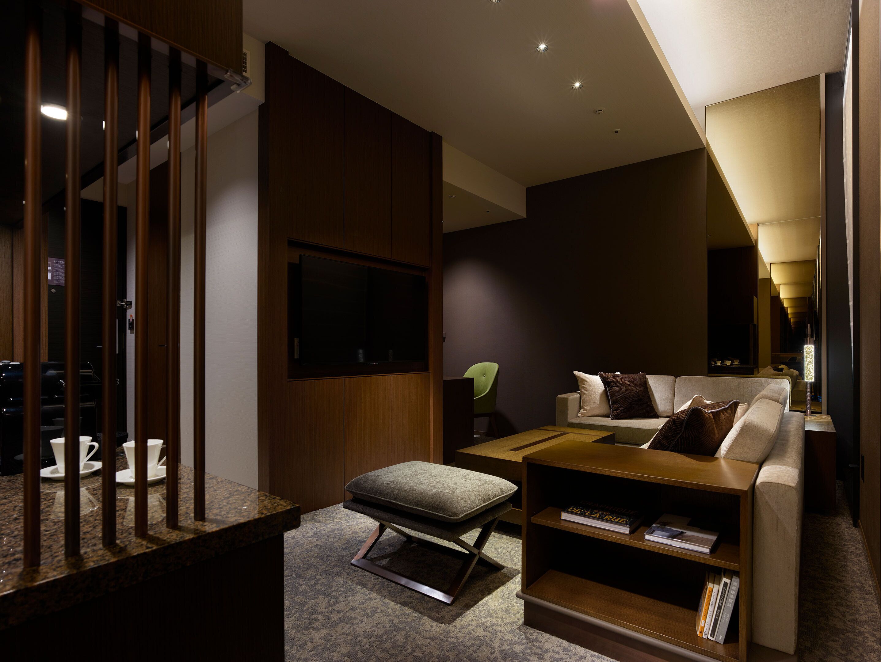 A modern living room with a sofa, ottoman, coffee table, and a bookshelf.