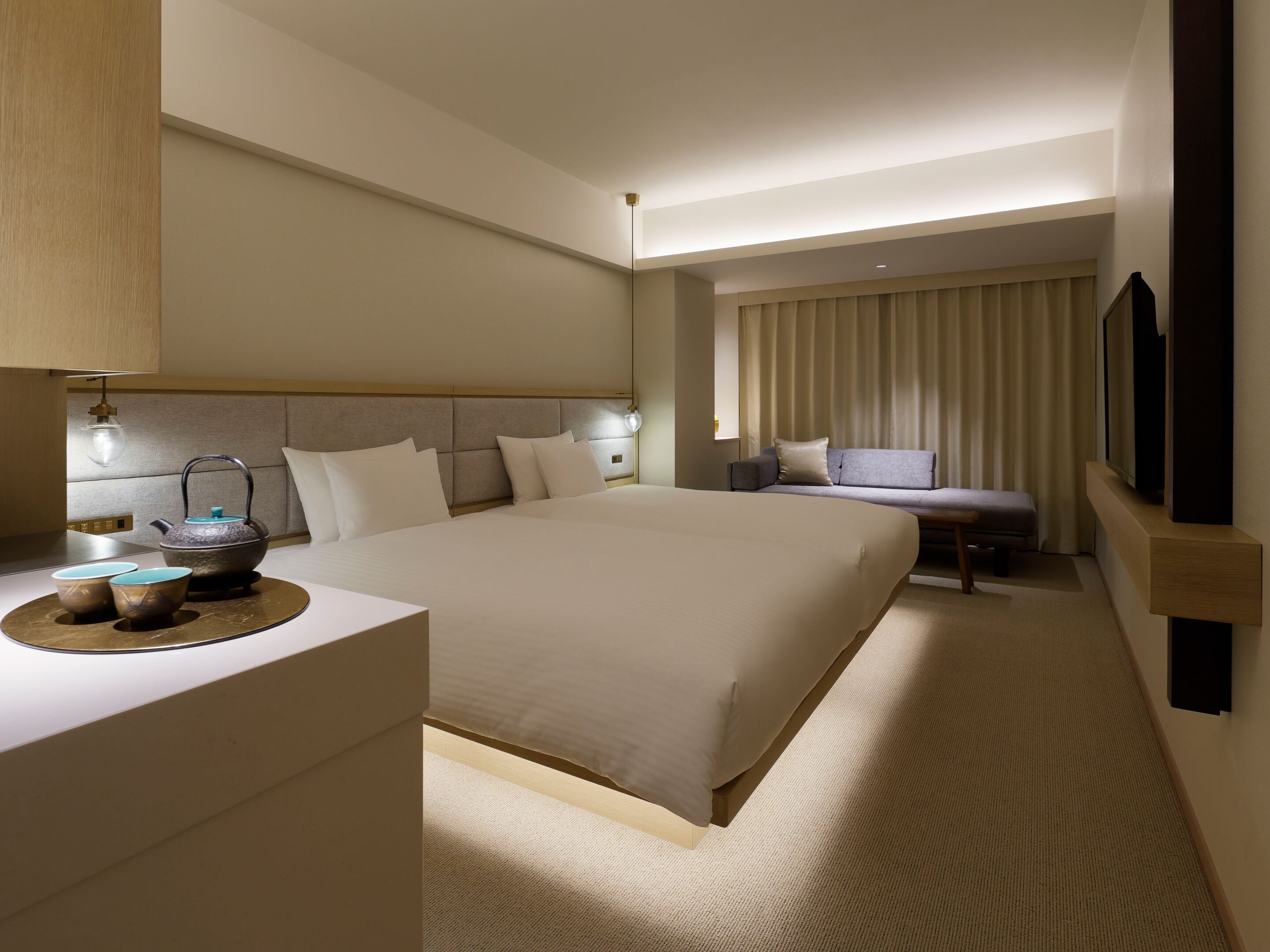 A hotel room with a large bed, bedside table, lamp, and a sofa.