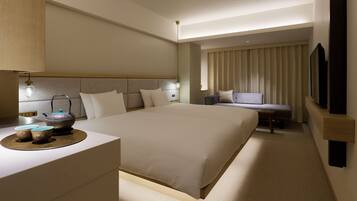 A hotel room with a large bed, bedside table, lamp, and a sofa.