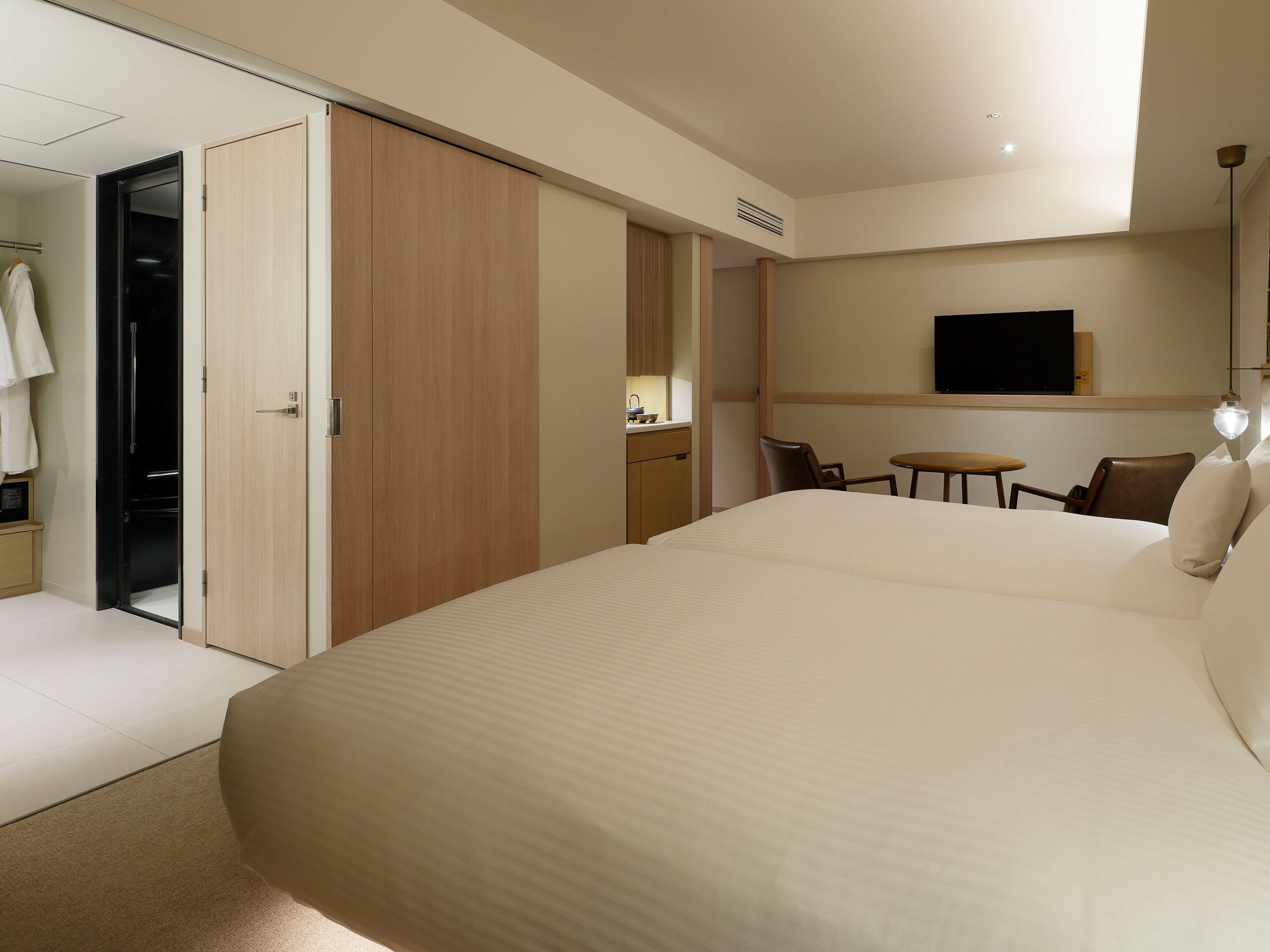 A hotel room with a large bed, a desk with a chair, a TV mounted on the wall, and a sliding door closet.