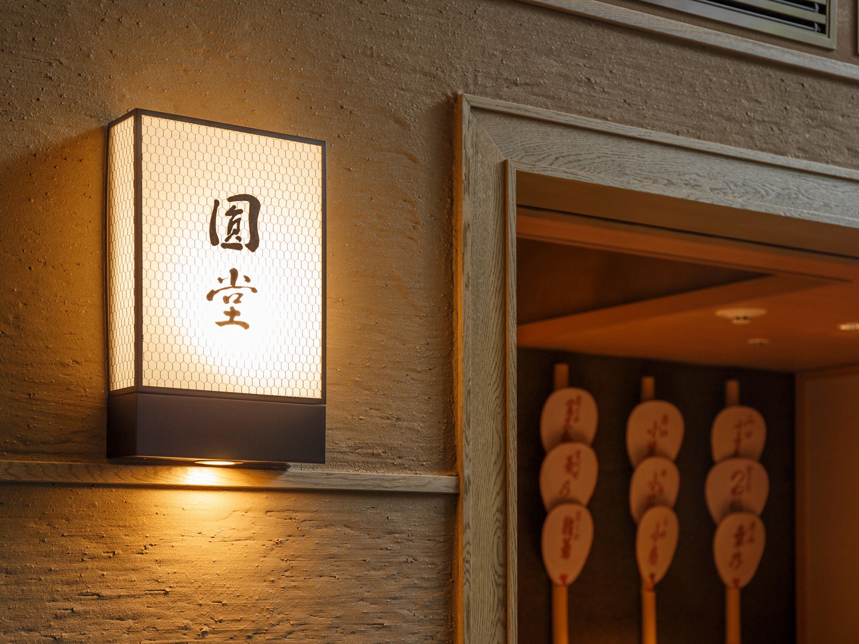 A traditional Japanese lantern with Chinese characters, a wooden wall, and a series of wooden signs with Chinese characters.