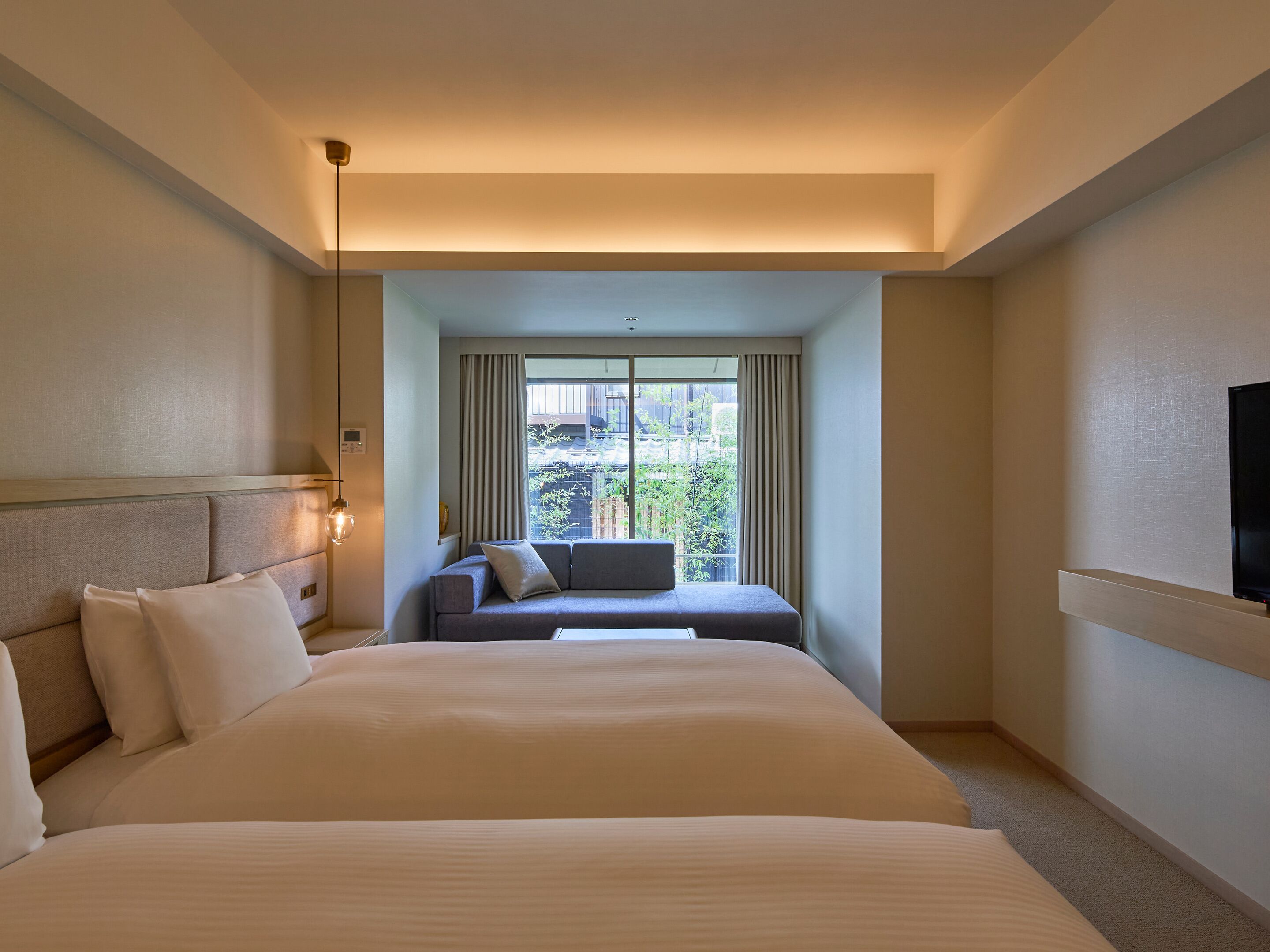 Ein Hotelzimmer mit einem großen Bett, einer Couch, einem Fernseher und einem Fenster mit Vorhängen.