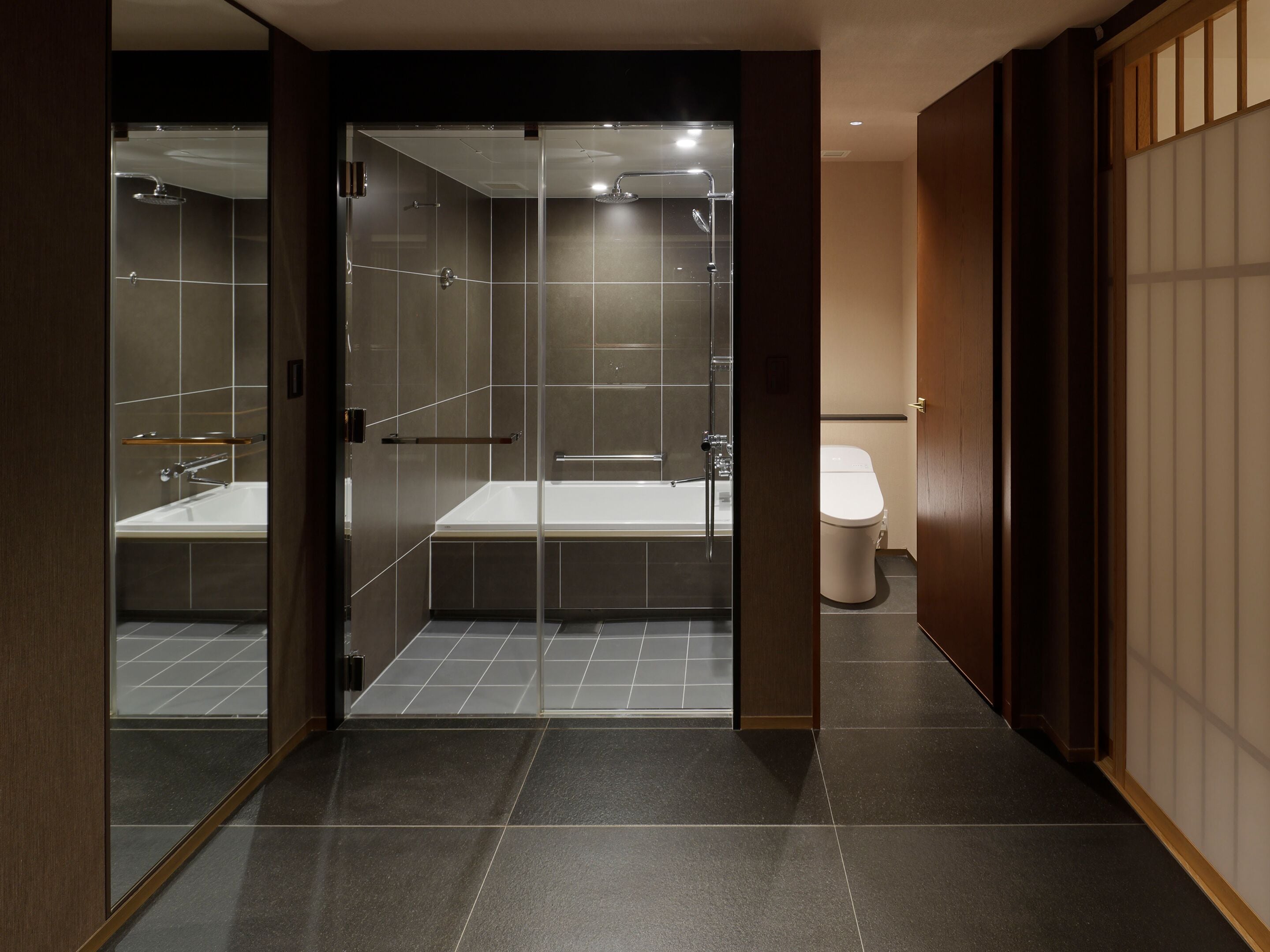 A modern bathroom with a glass-enclosed shower, a bathtub, and a toilet.