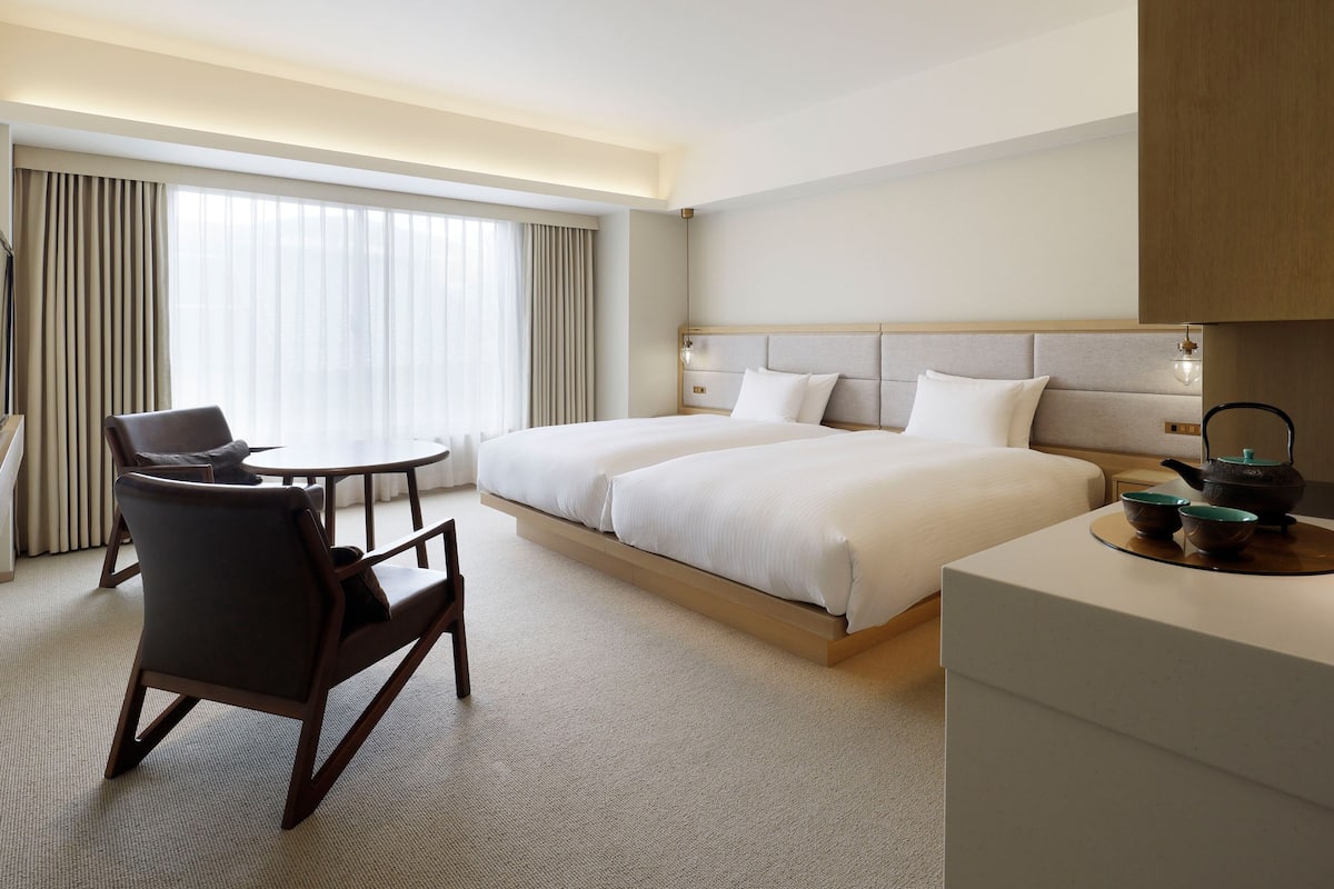 A hotel room with a bed, a desk, a chair, and a table.