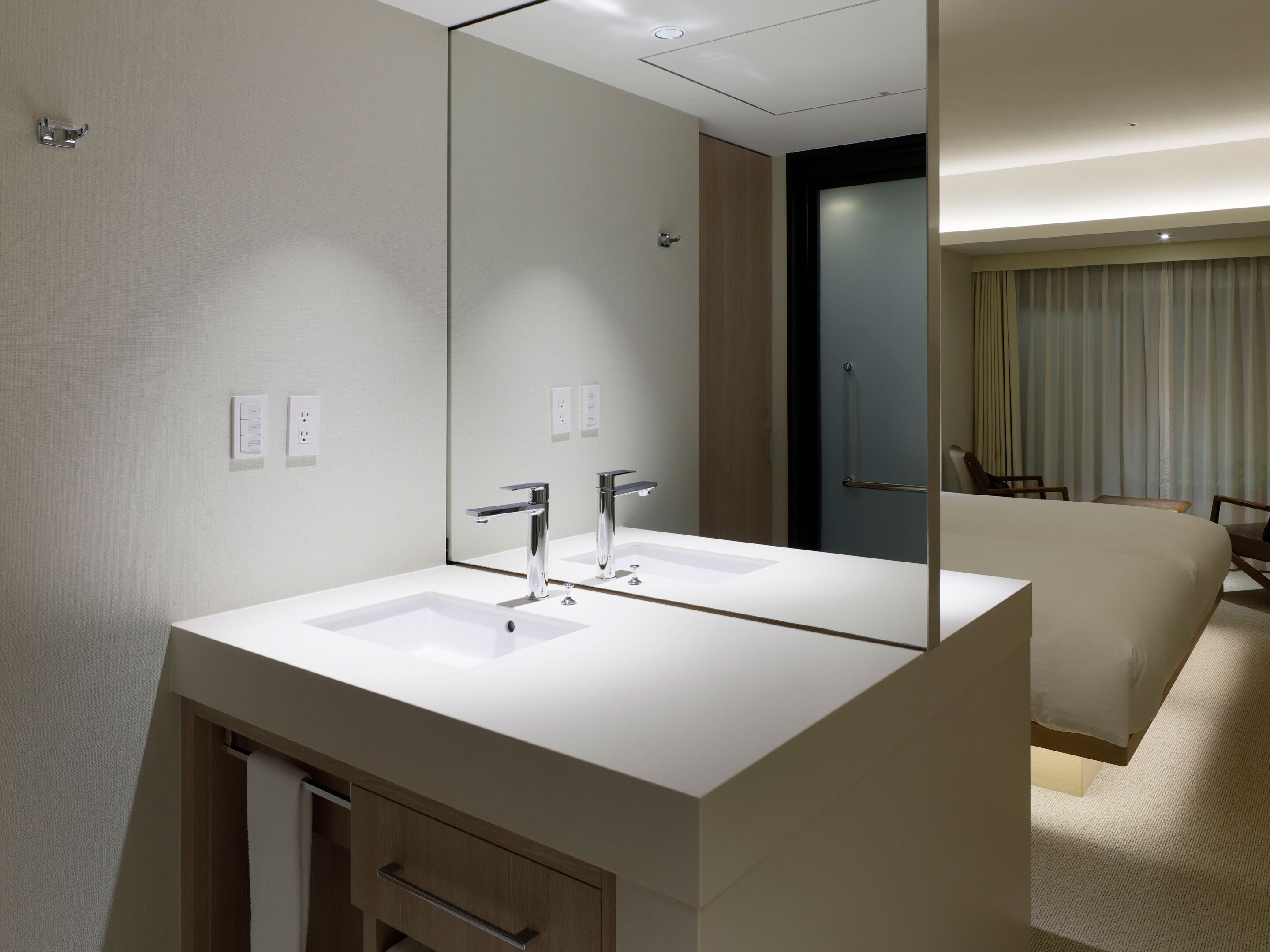 A modern bathroom with a large mirror, two sinks, and a wooden cabinet.