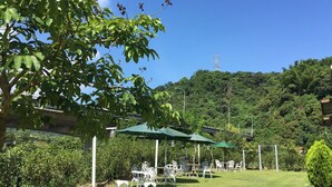 Un jardín con mobiliario exterior, una pérgola y vistas a una colina con una torre de líneas eléctricas.