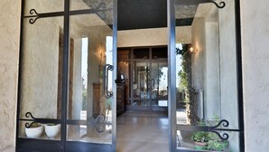 A glass door entrance with metal frames and a stone wall. - Le Mazet de Tourrettes (Tourrettes-sur-Loup)