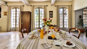A dining room with a table set for breakfast, including plates, glasses, and a vase of flowers. - Le Mazet de Tourrettes (Tourrettes-sur-Loup)