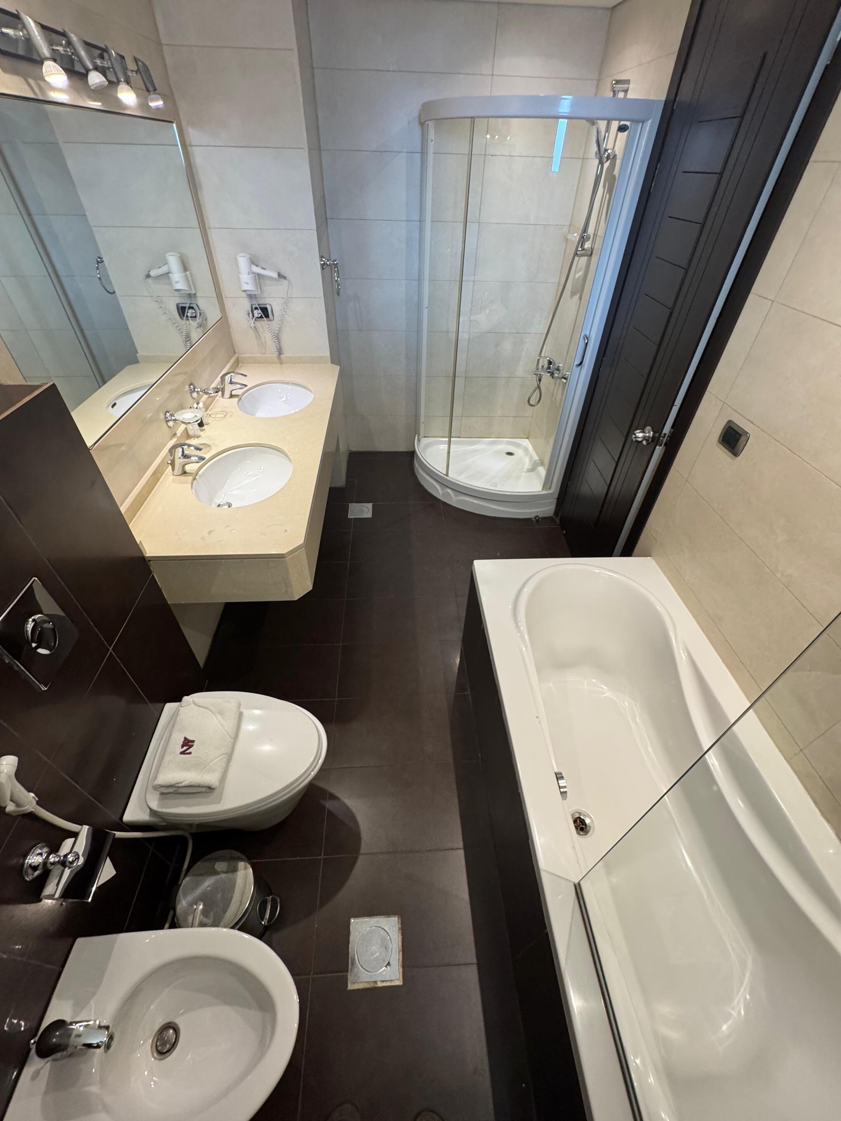 Ein modernes Badezimmer mit einer großen Badewanne, zwei Waschbecken, einer Toilette und einer Duschkabine.