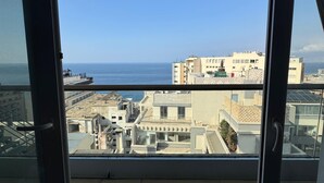 Un balcón con vista al mar y edificios.