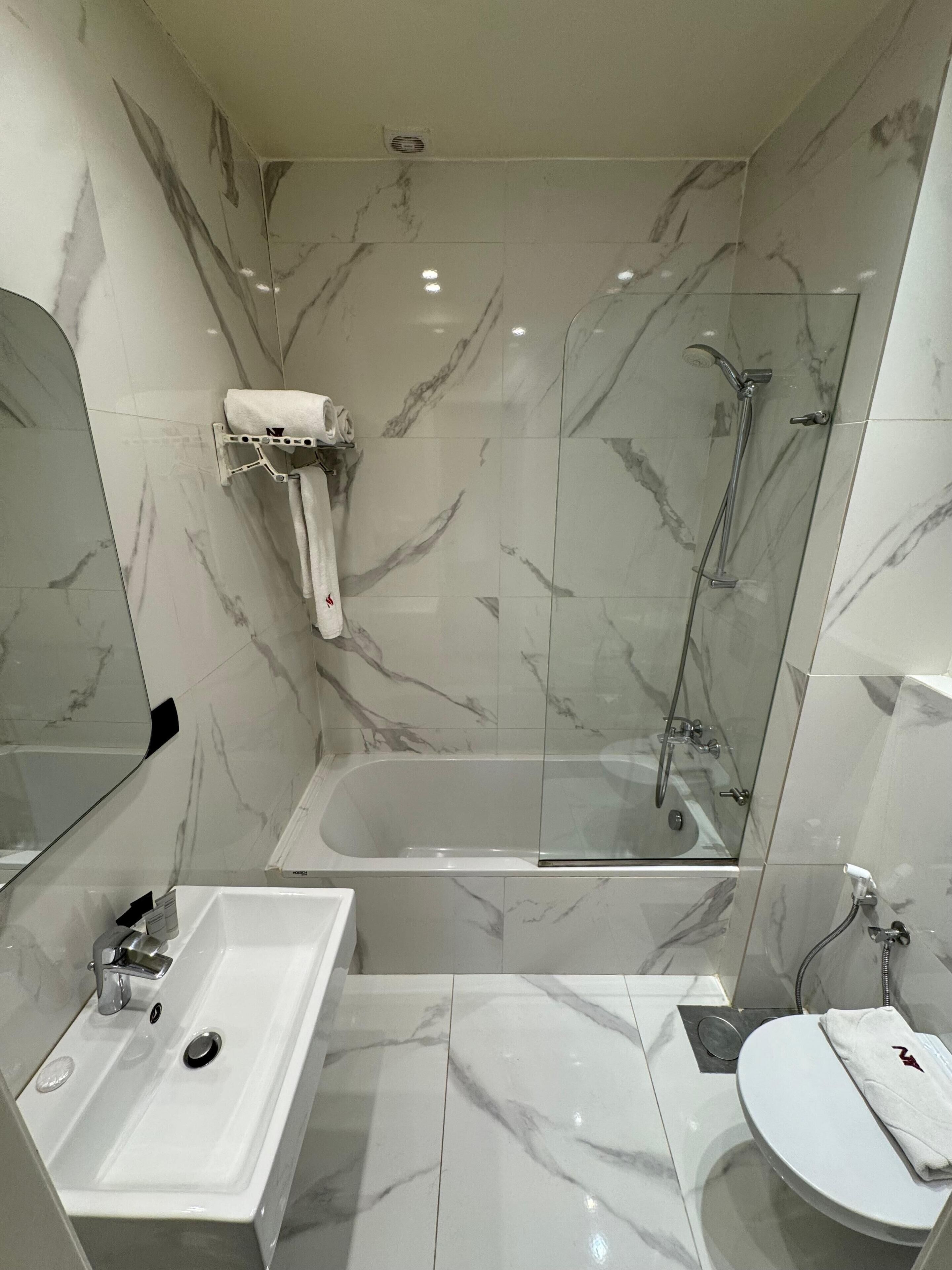 Et moderne badeværelse med et brusekabine i glas, et fristående badekar, en vask og et toilet.