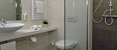 Un baño moderno con ducha de vidrio, lavamanos y retrete.
