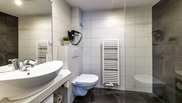A modern bathroom with a large white sink, a toilet, and a towel rack.