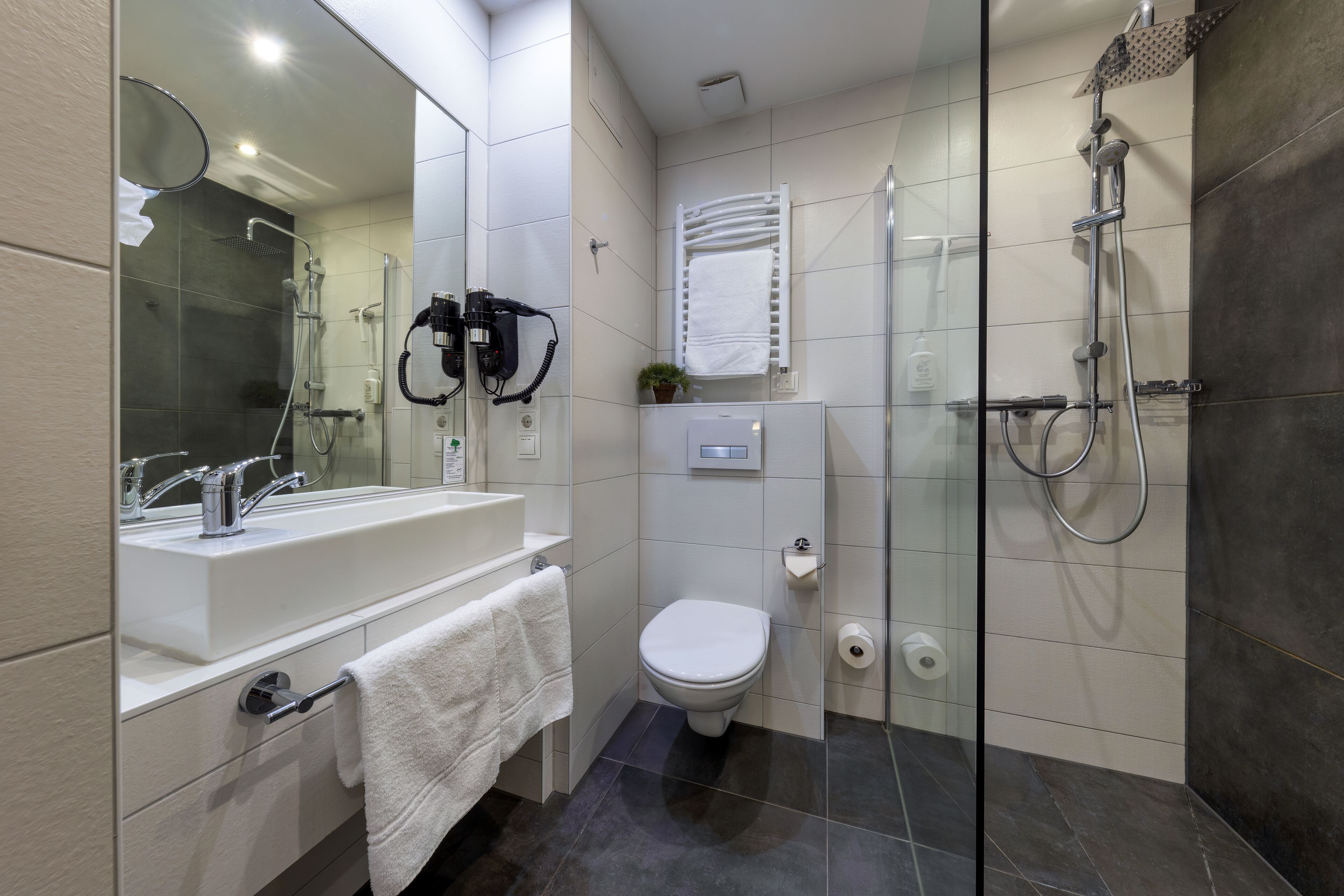 Un baño moderno con ducha acristalada, lavamanos blanco y un inodoro.