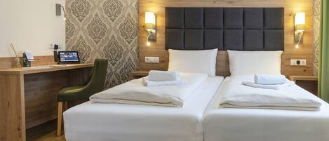 A hotel room with a double bed, a desk, a chair, and a laptop.