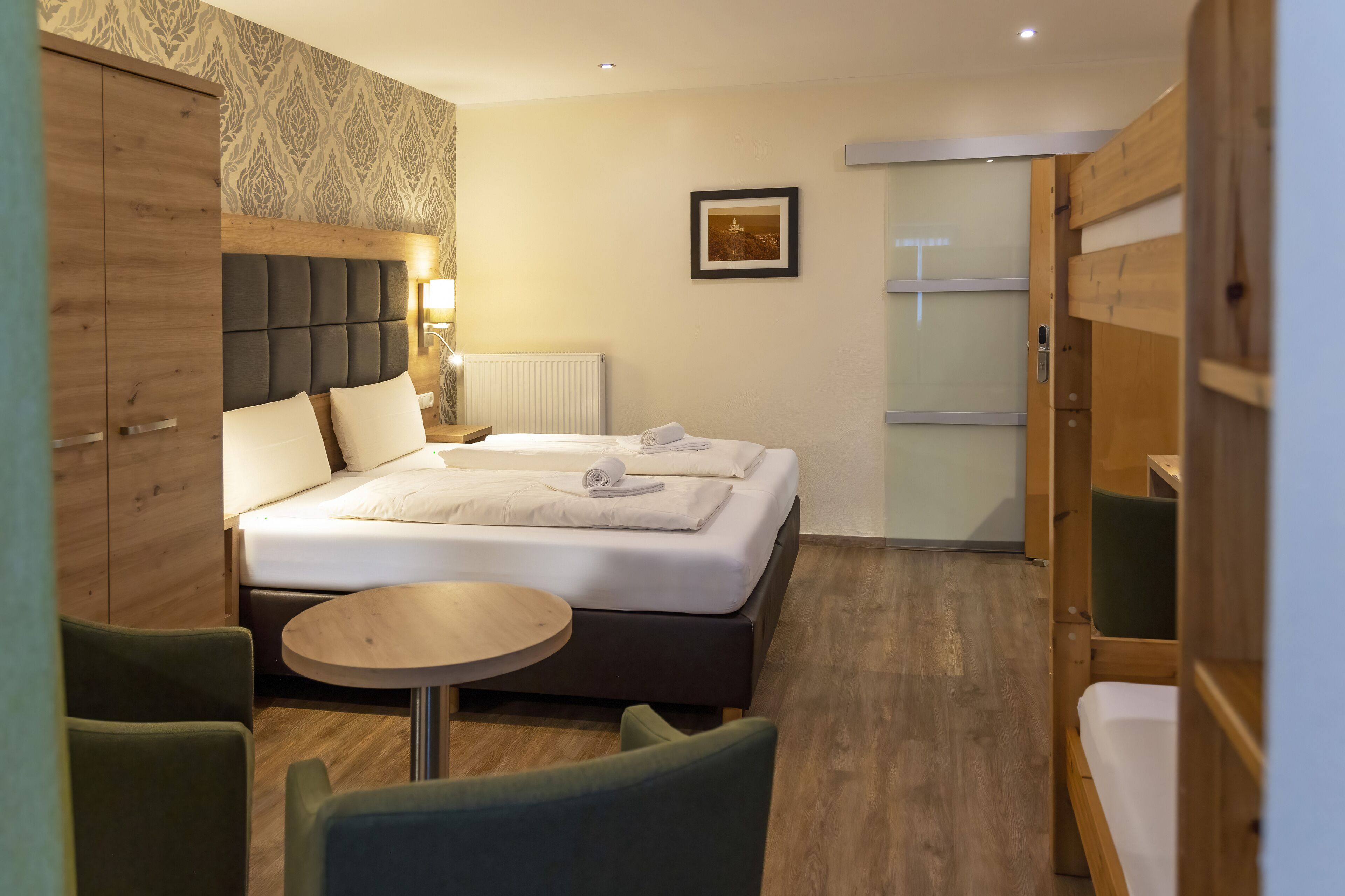 A hotel room with a bed, a round table, and two chairs.