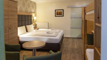 A hotel room with a bed, a round table, and two chairs.