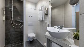 Ein modernes Badezimmer mit einer begehbaren Dusche, einer Toilette und einem Waschbecken mit Spiegel.