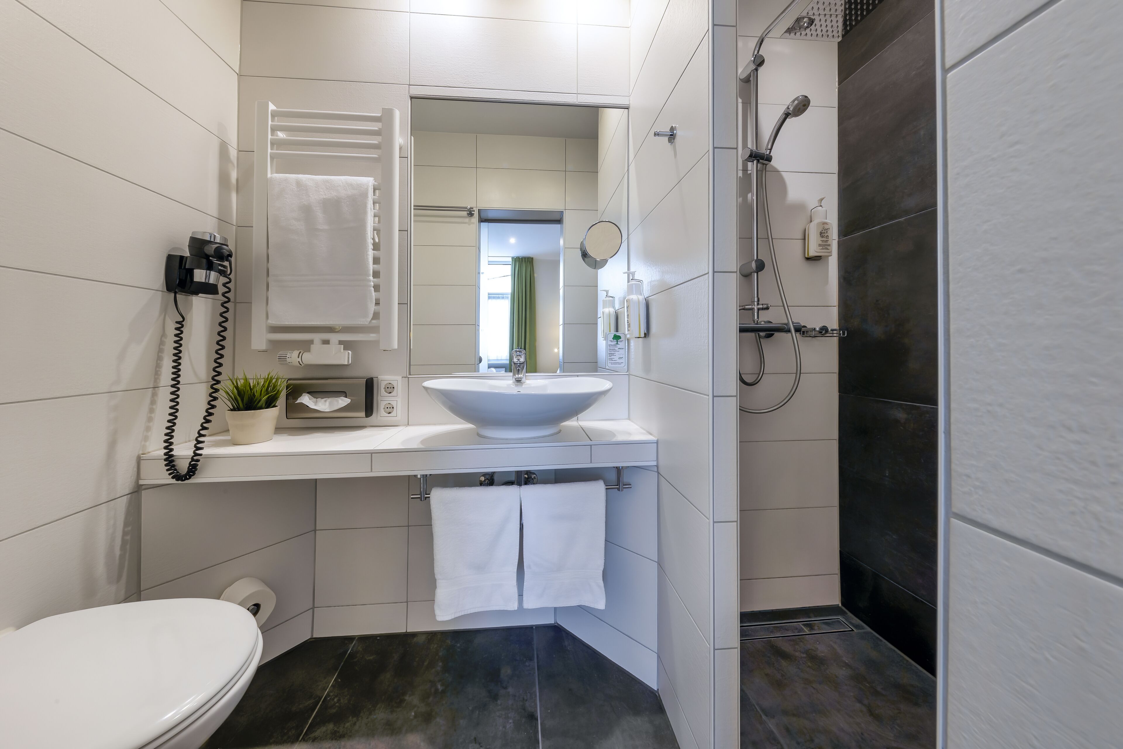 A modern bathroom with a white sink, a toilet, and a shower area.