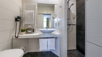 A modern bathroom with a white sink, a toilet, and a shower area.