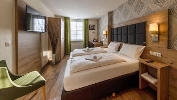 Ein Hotelzimmer mit einem großen Bett, einem Schreibtisch, einem Stuhl und einem an der Wand befestigten Fernseher.