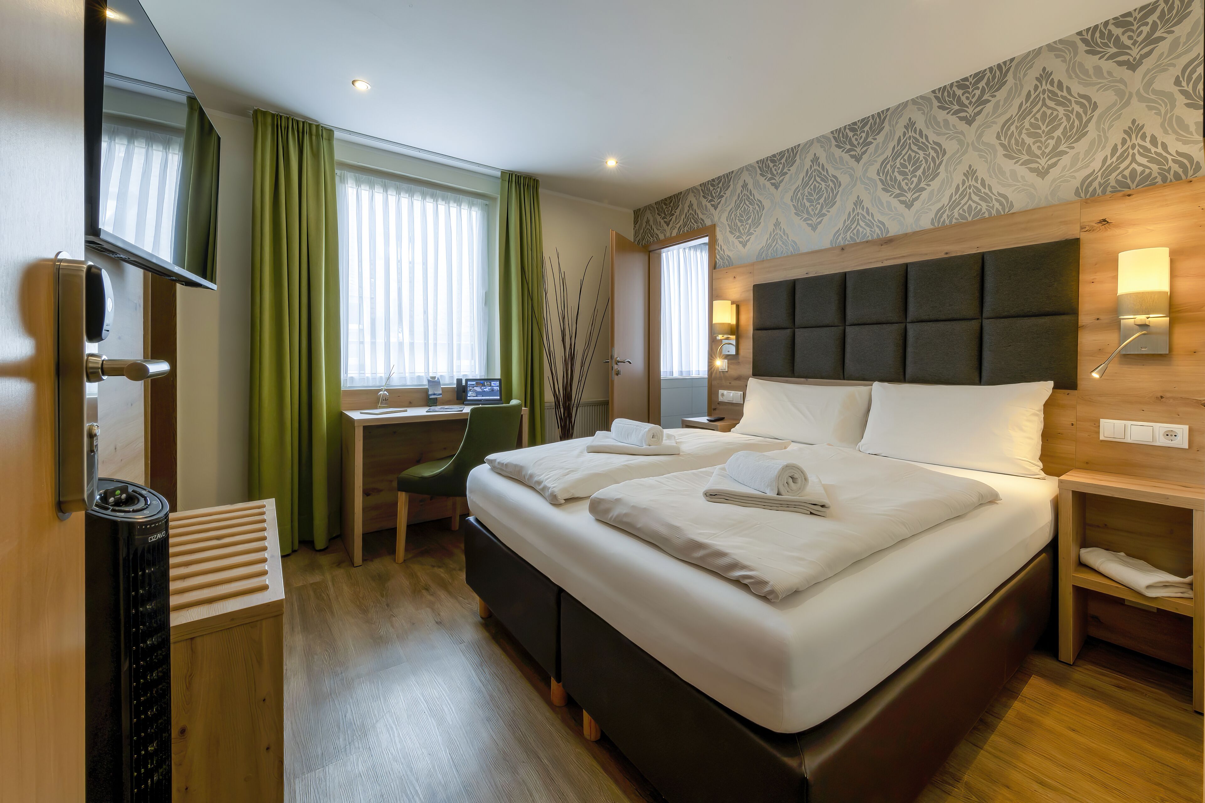 Une chambre d’hôtel avec un grand lit, un bureau, une chaise et un téléviseur.