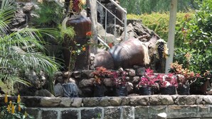 A garden with a stone wall, potted plants, and a large decorative barrel.