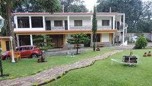 A two-story building with a balcony, a paved driveway, and a well-maintained lawn.