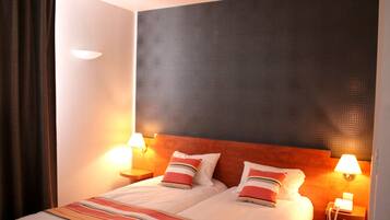 Una habitación de hotel con una cama, dos lámparas de noche y un teléfono en la mesita de noche.