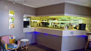 A bar area with a counter, bar stools, and a colorful chair. - Logis Hôtel Le Pélican & son restaurant (Vernantes)