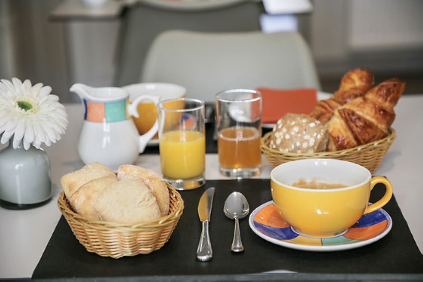 A breakfast setup with croissants, orange juice, and tea.
