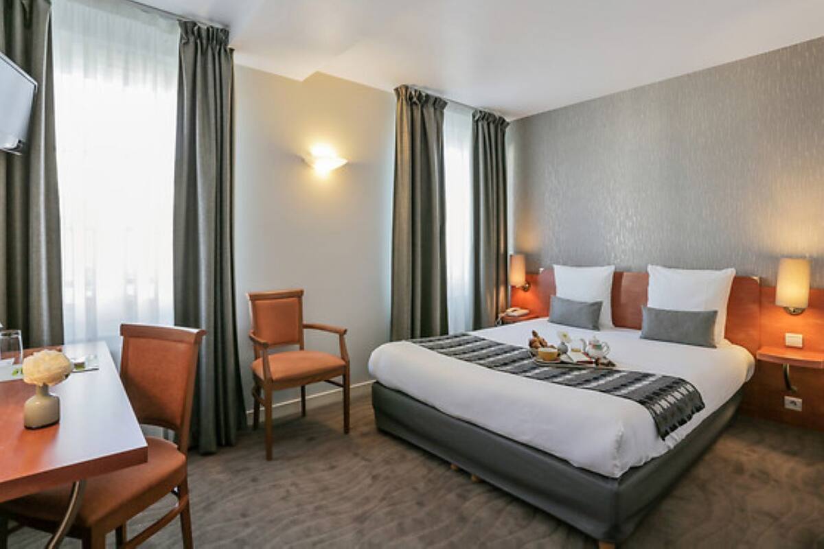 Ein Hotelzimmer mit einem Bett, einem Schreibtisch, einem Stuhl und einer Lampe.
