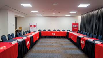 A conference room with a long table, red tablecloths, and chairs.