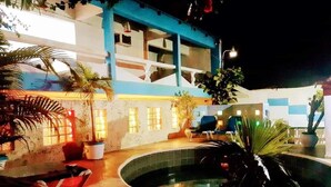A pool area with a circular pool, lounge chairs, and potted plants. - Hotel Tronco Inc (Boca Chica)